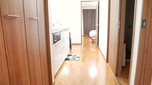 A narrow hallway with wooden flooring leading to a bedroom with a bed and a bathroom. - [Free Shuttle] Disney/Narita Airport/Tokyo [Family house]  (千葉市)
