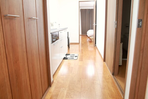 Un pasillo estrecho con suelo de madera que conduce a un dormitorio con cama y baño.