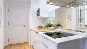 Ett modernt kök med vita skåp, en svart induktionshäll och en bänkskiva i trä.