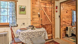 A rustic cabin interior with a dining table set for two, a wooden door, a fire extinguisher, and a radiator. - Rustic Hayward Cabin With Spider Lake Access! (Hayward)