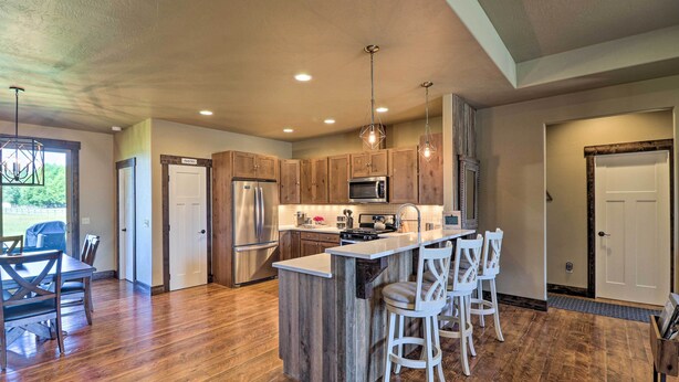 A modern kitchen with wooden cabinets, stainless steel appliances, and a central island with bar stools.
