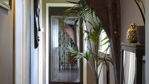 A wooden hallway with a large plant, a woven basket, and a pineapple decoration. - 16th century grade II* farmhouse with hot tub and wild swimming (Harleston)