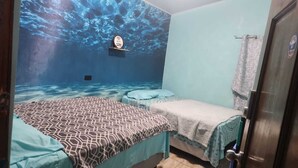 A room with a bed, a small table, and a wall mural of an underwater scene. - 3 bedroom Surf and Yoga House (Playa El Tunco)