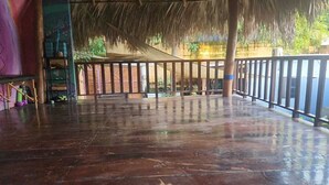 An indoor space with a thatched roof, wooden railings, and a tiled floor. - 3 bedroom Surf and Yoga House (Playa El Tunco)