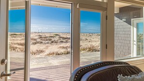 Une pièce dotée d’une grande porte vitrée donnant sur la plage, d’une terrasse en bois et d’une pancarte sur laquelle on peut lire : « BIENVENUE AU PARADIS ».