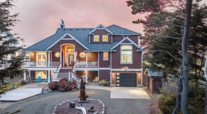 Une maison à deux étages avec un porche à l’avant, un garage et une allée.