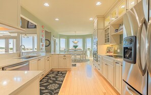 Een moderne keuken met een centraal eiland, roestvrijstalen apparatuur en grote ramen met uitzicht.