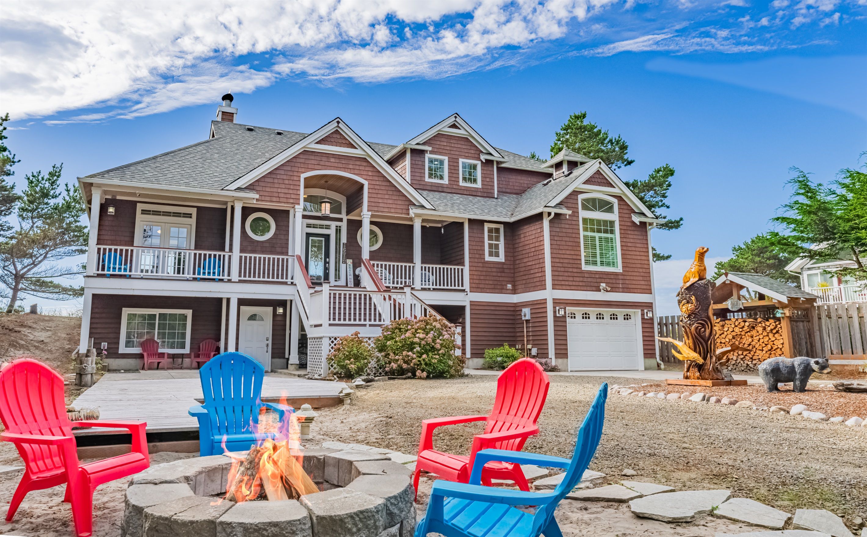 A two-story house with a porch, a fire pit, and outdoor seating.