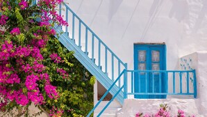 Un bâtiment blanc agrémenté de touches de bleu, avec un escalier et des fleurs roses.