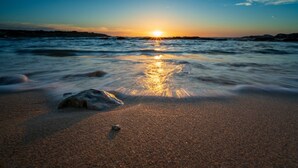 Une plage avec un coucher de soleil sur l’océan.