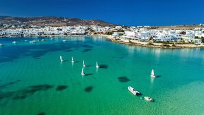 Vue aérienne d’une ville côtière, avec ses eaux turquoise limpides, ses bateaux et ses bâtiments blancs.