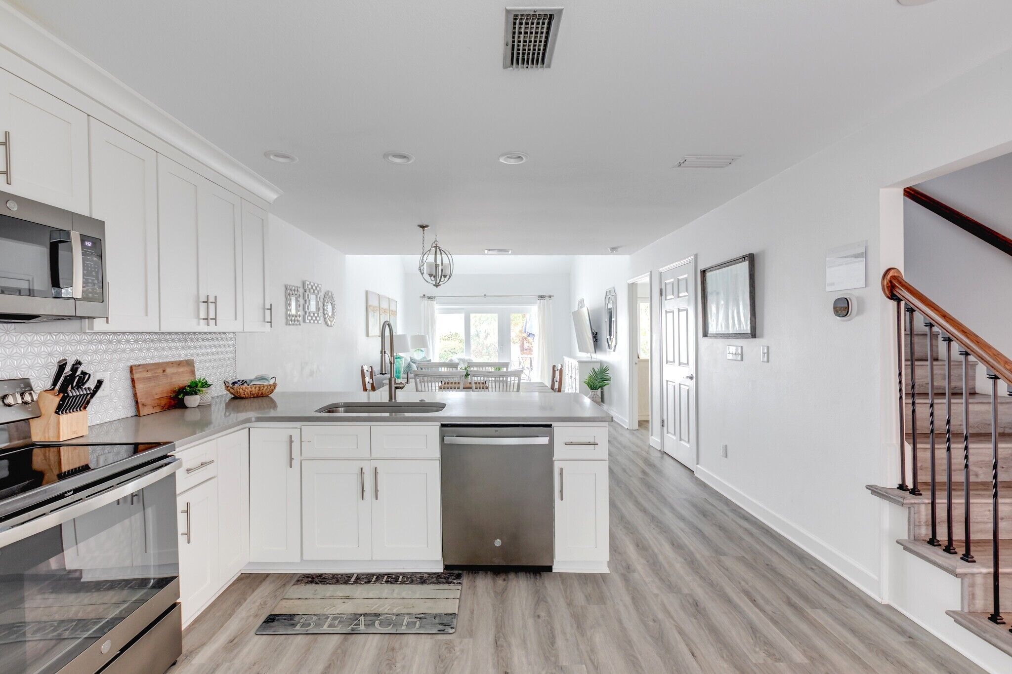 A modern kitchen with white cabinetry, a stainless steel dishwasher, and a central island.
