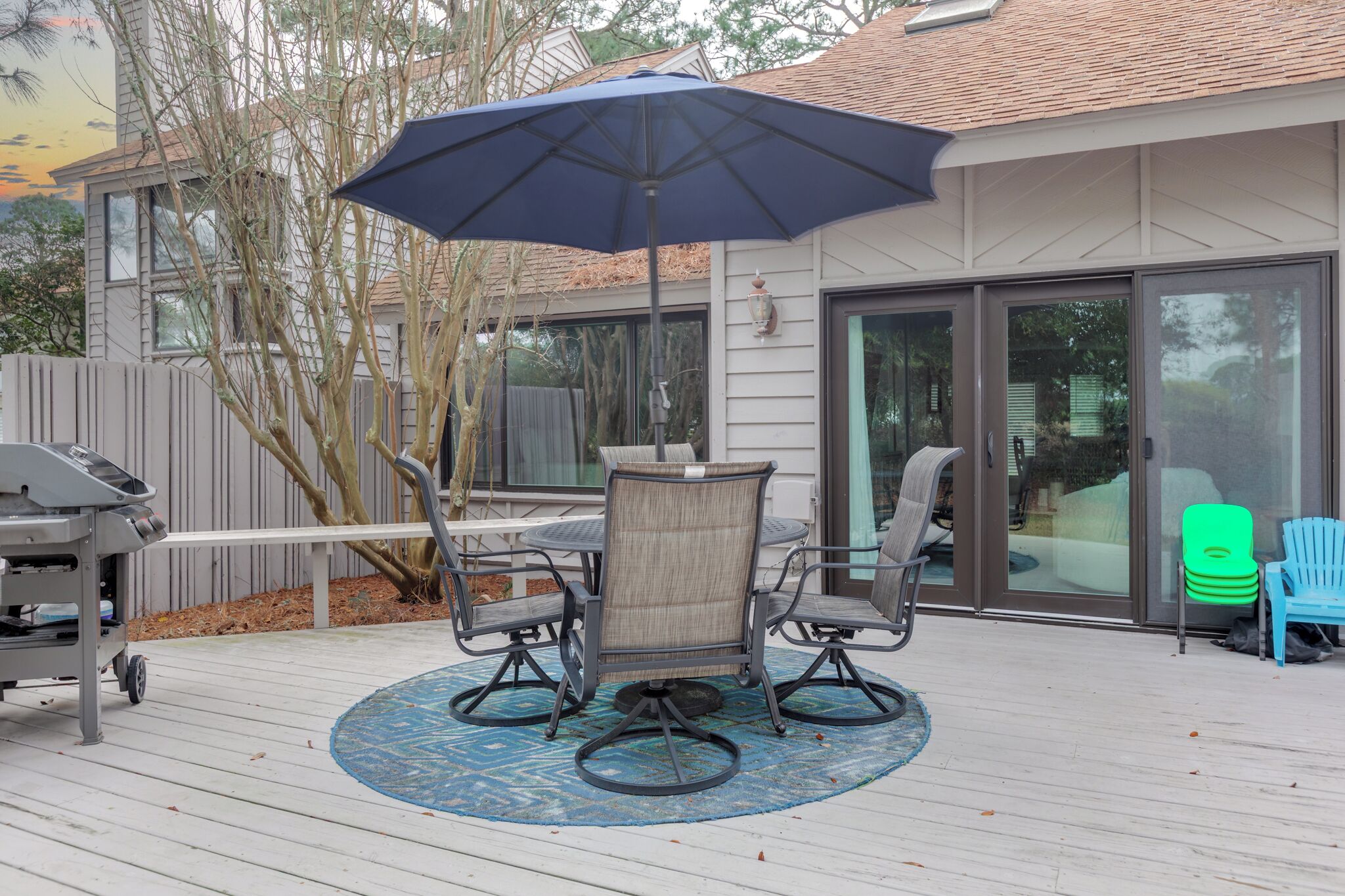 A patio with a table and chairs, an umbrella, and a grill.