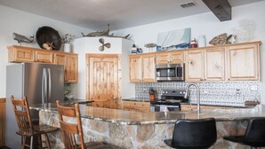 Una cocina con armarios de madera, una isla de piedra y taburetes de bar.