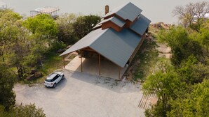 Una casa moderna con techo inclinado, un porche cubierto y un camino de entrada de grava.