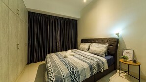 Een slaapkamer met een bed, een plafondventilator, een tafeltje met een plant en een donker gordijn.
