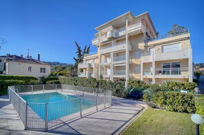 Un immeuble résidentiel à plusieurs étages doté d’une piscine et d’une terrasse clôturée.