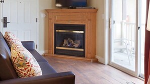 Una sala de estar con chimenea, un sofá y un ventanal corredizo que da a un espacio exterior.