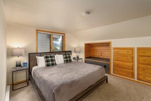 A bedroom with a bed, two bedside lamps, a window with blinds, a built-in wooden cabinet, and a ceiling light. - Unique condo w/treehouse features, fireplace and fantastic location - Stillwater Skyhouse Escape (Big Sky)