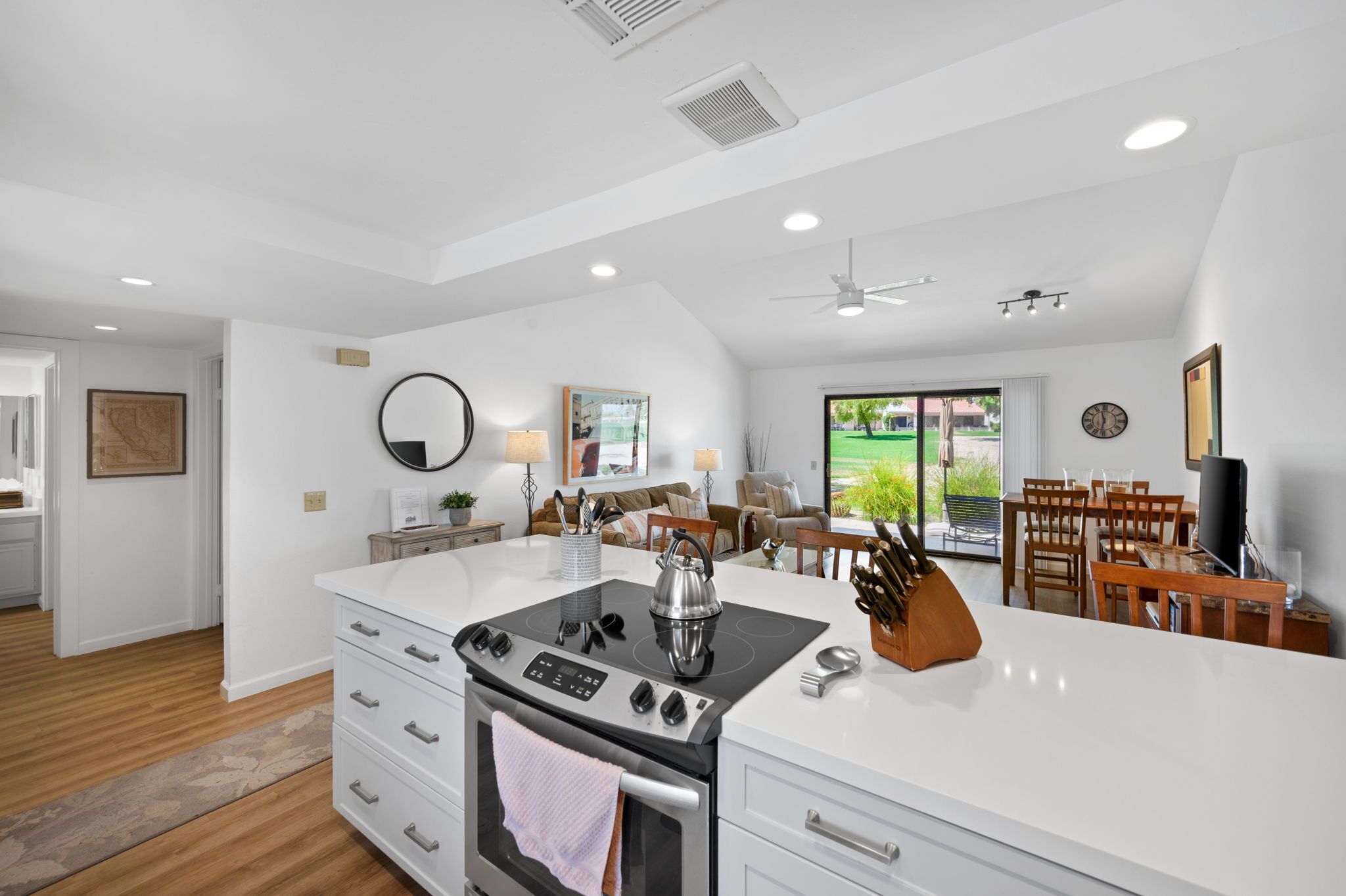 A modern kitchen with a central island, built-in oven, and a dining area with a table and chairs.