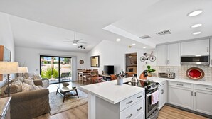 Une cuisine moderne avec des meubles blancs, un îlot central et un coin repas comprenant une table et des chaises.