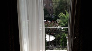 A balcony with a white chair, a glass table, and a view of a building with trees and a fence. - Cozy clean and bright studio8 (Arabkir)
