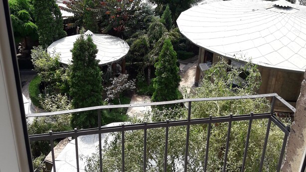 A view from a balcony overlooking a courtyard with a round building, trees, and parked cars. - Cozy clean and bright studio8 (Arabkir)
