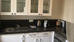 Una cucina con mobili bianchi, un piano di lavoro nero, un bollitore, un tostapane e un fornello.