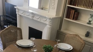Tavola imbandita per quattro con piatti bianchi, bicchieri da vino e posate. Sul tavolo c'è anche una piccola pianta in vaso.
