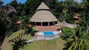 A resort with a thatched-roof structure, a swimming pool, and lush tropical surroundings. - Tres Palmas Costa Rica (Puerto Jiménez)