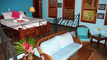Quarto de hotel com cama, sofá, cadeira e pequena mesa com um vaso de flores.