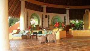 A spacious lobby with a tiled floor, seating area with sofas and chairs, and a staircase leading to an upper level. - Tres Palmas Costa Rica (Puerto Jiménez)