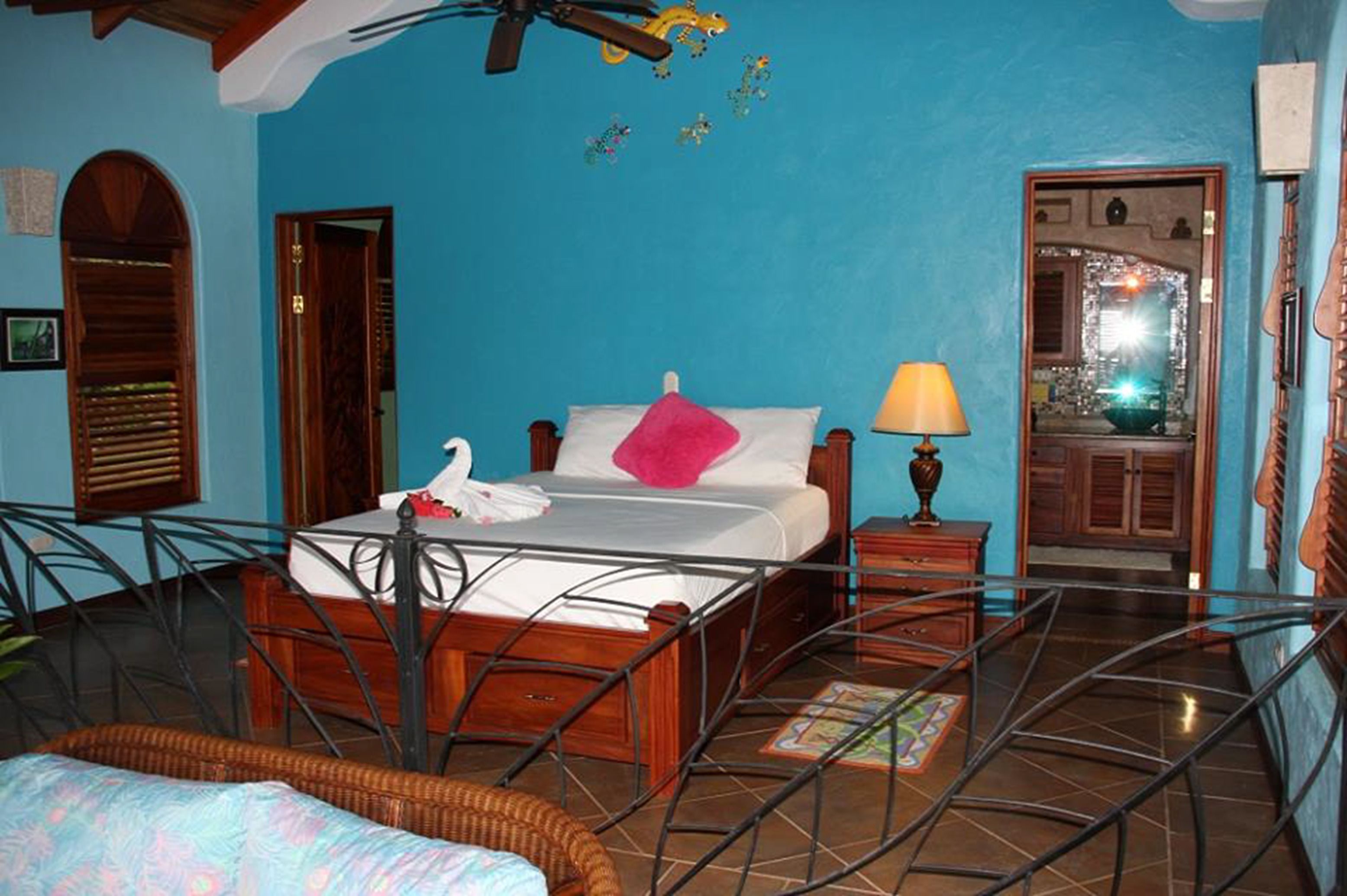 A room with a bed, a chair, a lamp, and a mirror.