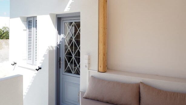 A white exterior wall with a blue door, a wooden beam, and a light fixture.