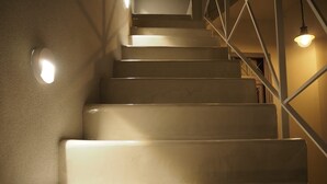 A staircase with a handrail and wall-mounted lights.