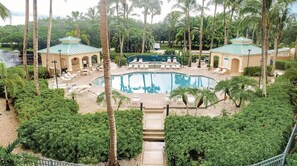 Uma área de piscina com espreguiçadeiras e palmeiras.