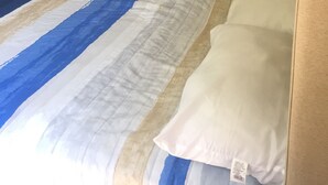 Una camera da letto con un letto, un armadio scuro e un bagno visibile attraverso una porta aperta.