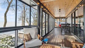 Una terraza techada con vista a la playa, amueblada con un sofá, sillas y una mesa.