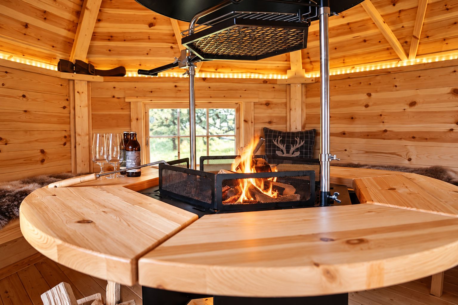A wooden interior with a round table, a fireplace, and a window.