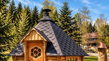 Une cabane en rondins avec une fenêtre hexagonale, une cheminée et une porte.