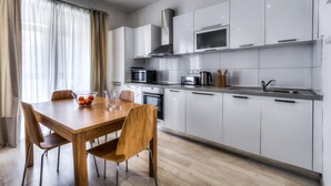 A modern kitchen with white cabinets, stainless steel appliances, and a wooden dining table. - Perfectly Located Sliema Apartment (Sliema)