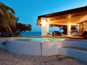 A poolside area with a view of the ocean, a thatched roof structure, and lounge chairs. - Beachfront villa-Private beach-Pool Romantic  (Placencia)