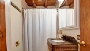 A bathroom with a wooden vanity, a mirror, and a shower curtain. - Cabin in the Pines, Prescott, AZ (Prescott)