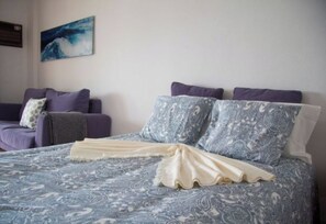 A bedroom with a bed, a sofa, and a wall-mounted artwork. - Wonderful apartment right on the beach (Costa da Caparica)