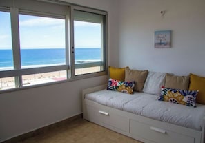 Une chambre avec un lit, une fenêtre donnant sur la plage et un panneau fixé au mur.