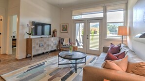 Ein Wohnzimmer mit einer Couch, einem Couchtisch, einem Fernseher und Blick durch Glastüren.