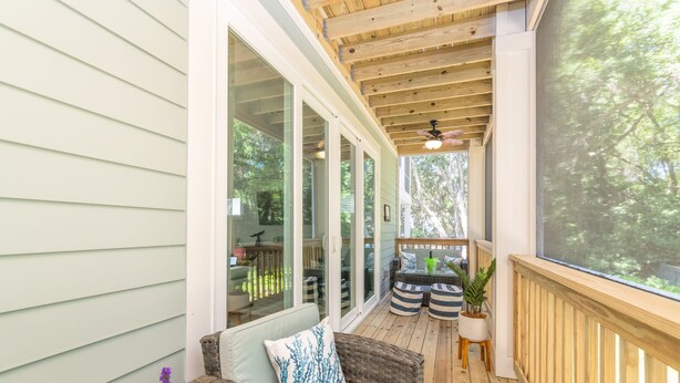 A covered porch with wicker furniture, a ceiling fan, and a view of the surrounding trees. - 115 Luxury Pool Home | Elevator | Kid's Playroom (Hilton Head Island)