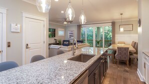 A modern kitchen with granite countertops, a sink, and pendant lighting. - 115 Luxury Pool Home | Elevator | Kid's Playroom (Hilton Head Island)