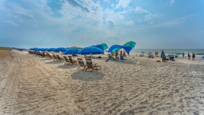 A beach with rows of blue umbrellas and beach chairs. - 115 Luxury Pool Home | Elevator | Kid's Playroom (Hilton Head Island)