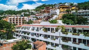 A multi-story hotel with balconies, located on a hillside with other buildings. - Luxury Condo Romantic Zone-Beach (Puerto Vallarta)